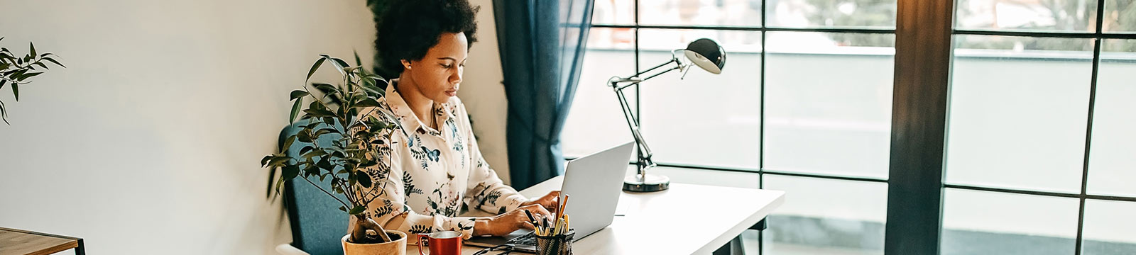 a woman at her home desk working on a laptop