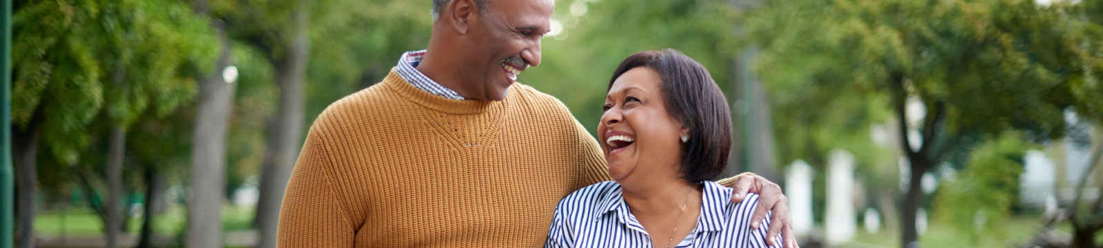 a mature couple smiling while walking in a park